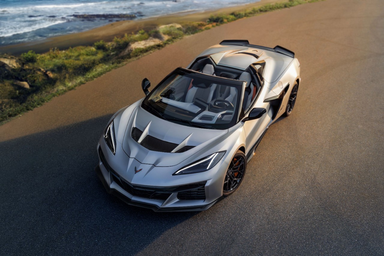 A silver convertible sports car parked near a scenic ocean vista.